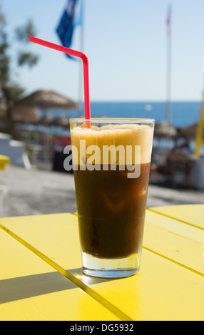 Un freddo, spumosi bicchiere di 'espresso fredo' iced caffè nero su un tavolo del bar. La Grecia, 2013. Foto Stock