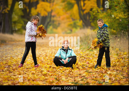 La madre a giocare con i bambini nel parco in autunno Foto Stock