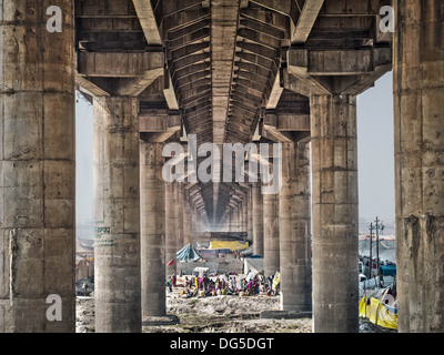 Le persone e le tende sotto il ponte principale attraversando la massiccia Kumbh Mela 2013 festival di Allahabad, India. Foto Stock