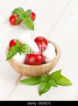 Mozzarella con pomodorini e basilico bianco sul tavolo di legno Foto Stock