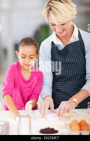 Graziosa bambina con la nonna i biscotti di cottura in cucina Foto Stock