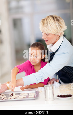 Graziosa bambina con la nonna i biscotti di cottura insieme a casa Foto Stock