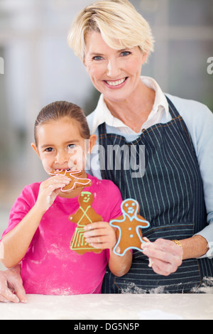 Bellissima bambina mangiare gingerbread cookie la sua nonna appena cotti Foto Stock