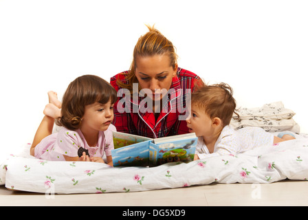 Madre alla lettura della storia per i suoi bambini nel letto prima di dormire Foto Stock