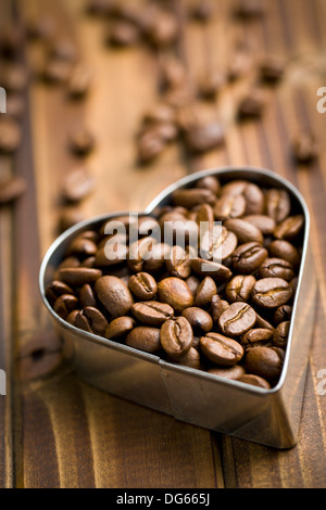 I chicchi di caffè a forma di cuore sul tavolo di legno Foto Stock