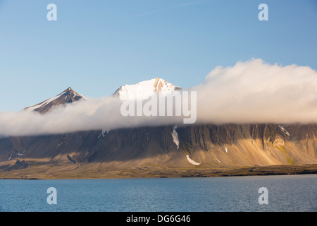 Un picco di montagna, sbirciando attraverso il cloud a Bourbonhamna 77° 33' N 15°00'e; Spitsbergen Svalbard. Foto Stock