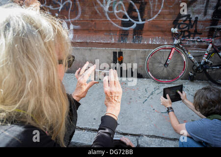 New York, Stati Uniti d'America. Il 15 ottobre 2013. Street appassionati d arte gregge per il quartiere Tribeca di New York Martedì, Ottobre 15, 2013 per vedere la quindicesima puntata di Banksy dell arte dei graffiti, 'Tribecca'. Il fantomatico artista di strada è la creazione di opere intorno alla città ogni giorno durante il mese di ottobre e che questo episodio mostra una silhouette del World Trade Center con un fiore attaccato. Credito: Richard Levine/Alamy Live News Foto Stock