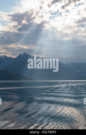 Streaming di luce del sole attraverso le nuvole nel Glacier Bay in Alaska, durante una crociera in Alaska. Foto Stock