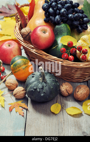 Fresche e mature zucche, mele, uva e i dadi nel cesto in vimini su sfondo di legno Foto Stock