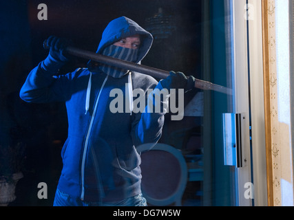 Un ladro che cerca di entrare in una casa dalla porta posteriore Foto Stock