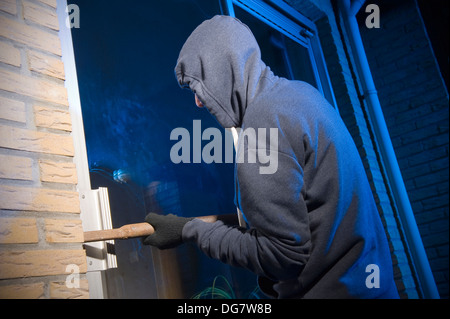 Un ladro sta cercando di entrare in una casa dalla porta posteriore Foto Stock