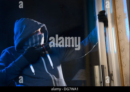 Un ladro sta cercando di entrare in una casa dalla porta posteriore Foto Stock