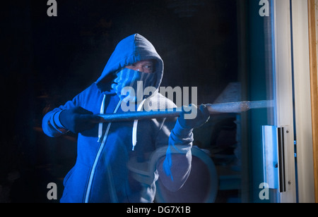 Un ladro che cerca di entrare in una casa dalla porta posteriore Foto Stock