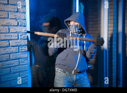 Un ladro che cerca di entrare in una casa dalla porta posteriore Foto Stock