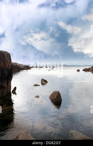 Vista panoramica in kerry in Irlanda di rocce e mare con montagne contro un bel blu cielo molto nuvoloso Foto Stock