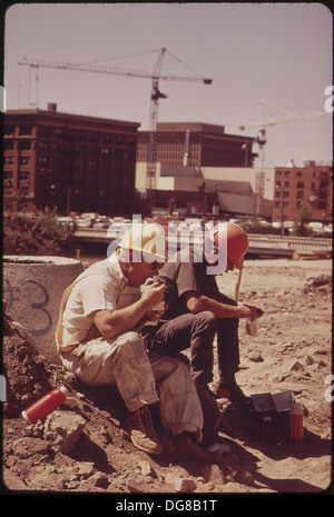 I lavoratori edili fanno una pausa pranzo presso il sito dell'Expo '74, affacciato sul fiume Columbia, durante i preparativi per la fiera mondiale tenutasi a Spokane, Washington, evidenziando il lavoro coinvolto nella preparazione dell'evento. Foto Stock