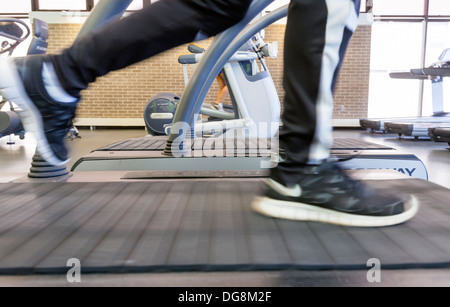 Un uomo che corre su un tapis roulant in una palestra per esercizi. Foto Stock