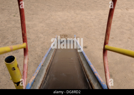 Un vecchio parco giochi scorrere in corrispondenza di un parco giochi per bambini Foto Stock