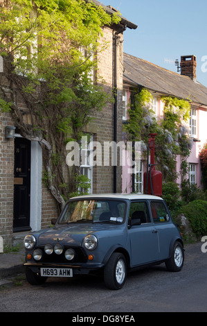 Classic car. Una Austin Mini parcheggiata nella strada alta del pittoresco villaggio di Dorset di Sydling St Nicholas. Dietro di esso è un vintage pompa benzina. In Inghilterra. Foto Stock