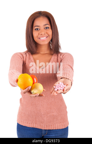 Donna africana e la sua scelta - pillole o frutta isolato Foto Stock