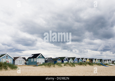 Una fila di cabine sulla spiaggia, su Hengistbury head beach. Vacanza familiare destinazione balneare. A strapiombo nuvole grigio. Foto Stock