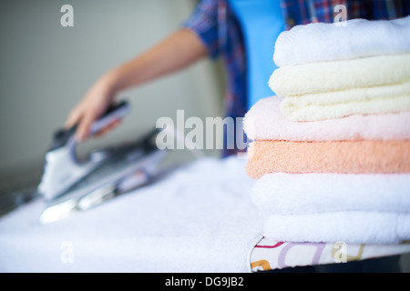 Pila di asciugamani puliti sullo sfondo della femmina di stiratura Foto Stock