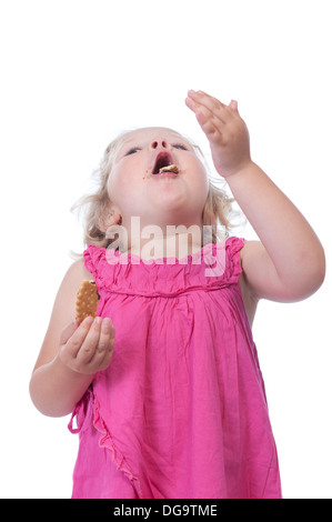 Bambina in rosa di mangiare un biscotto, isolato su sfondo bianco Foto Stock