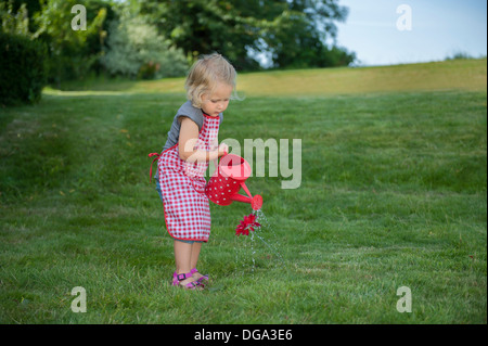 Bambina con annaffiatoio, all'aperto in giardino Foto Stock
