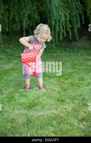 Bambina con annaffiatoio, all'aperto in giardino Foto Stock
