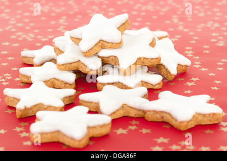 Molti a forma di stella cannella biscotti su sfondo rosso con stelle dorate Foto Stock