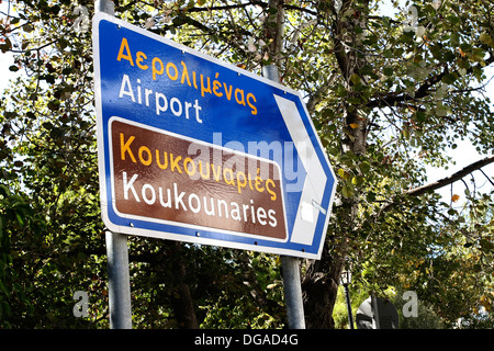 Un segno in inglese e greco dirigere i turisti all'aeroporto e per la spiaggia Koukounaries sull'isola greca di Skiathos. Foto Stock