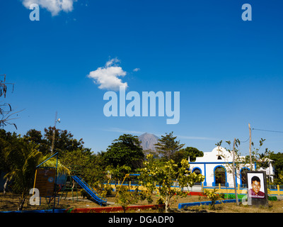 Parco giochi per bambini vicino alla chiesa sulla isola di Ometepe Nicaragua vista della concezione attivo vulcano in aumento in background a poche miglia di distanza Foto Stock