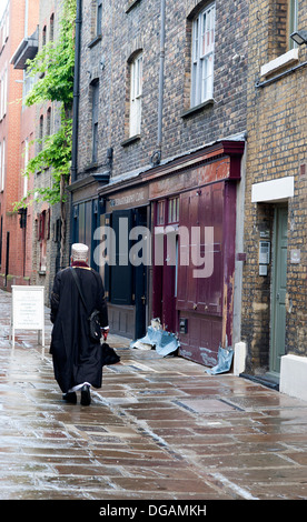 Etnicamente vestito uomo a camminare lungo la vecchia strada asfaltata nella zona est di Londra. Foto Stock