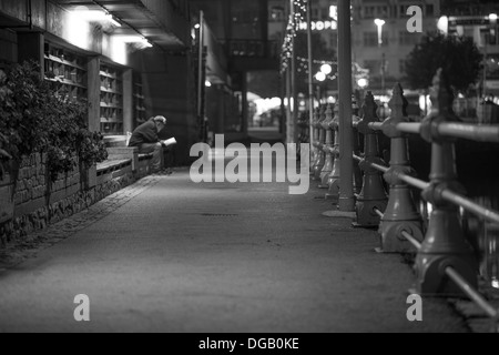 Lonely vecchio maschio libro lettura di notte Torquay Devon in bianco e nero Foto Stock