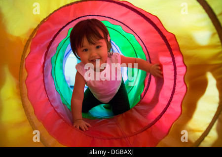 Baby girl strisciando attraverso il tunnel di riproduzione Foto Stock