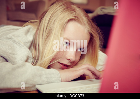 Ragazza giovane disteso sul pavimento con laptop Foto Stock