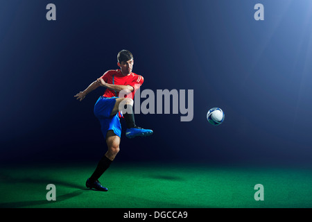 Maschio giovane giocatore di calcio calci palla Foto Stock