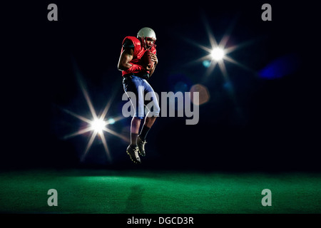 Giocatore di football americano metà aria con sfera Foto Stock