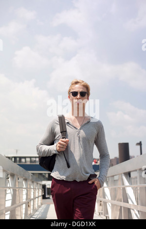 Giovane uomo che cammina sulla passerella di Brooklyn, a New York City, Stati Uniti d'America Foto Stock