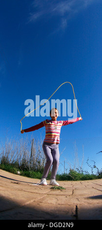 Una ragazzina salta una corda. Foto Stock