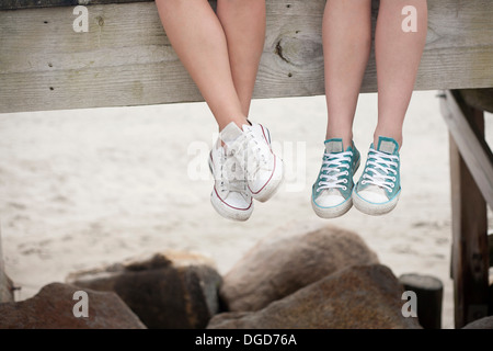 Giovani donne seduta sul molo sulla spiaggia, sezione bassa Foto Stock