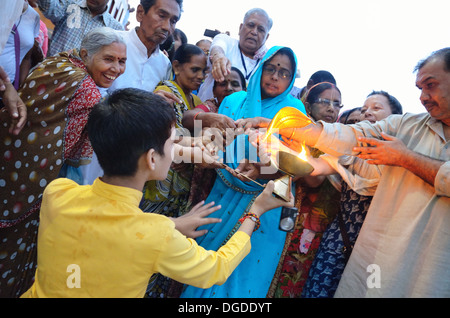 I devoti prelevando il calore del fuoco sacro dal Aarti, serata Ganga Aarti presso il Parmarth Niketan ashram a Rishikesh, India Foto Stock