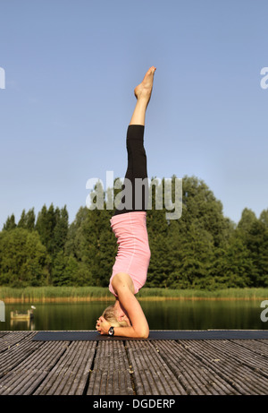Donna fare yoga headstand in posizione di parcheggio Foto Stock