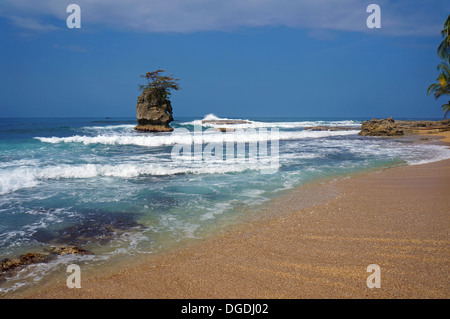 Spiaggia di sabbia con isolotto roccioso e di onde che si infrangono sulla barriera corallina, Costa Rica, Manzanillo Foto Stock