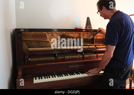 Il vecchio uomo tuning un canadese-fatti grande pianoforte verticale Foto Stock