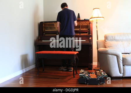 Il vecchio uomo tuning un canadese-fatti grande pianoforte verticale Foto Stock