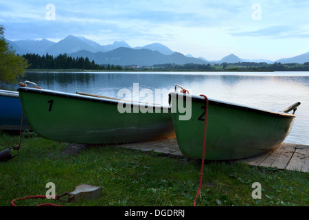 Barche in un lago delle Alpi dell'Algovia orientale (Baviera, Germania) durante il tramonto. Foto Stock