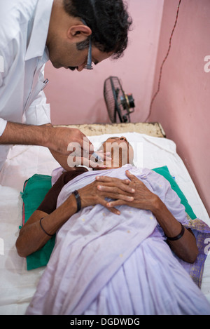L'aspirazione con ago fine patologo estrazione delle celle in un grumo di un paziente di sesso femminile al Sathya Sai Mobile Ospedale outreach Foto Stock