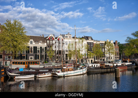 Case a schiera, barche e chiatte lungo il fiume Amstel di Amsterdam, in Olanda. Foto Stock