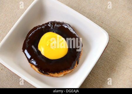 Ciambella di cioccolato sulla piastra isolata su uno sfondo di tessuto Foto Stock